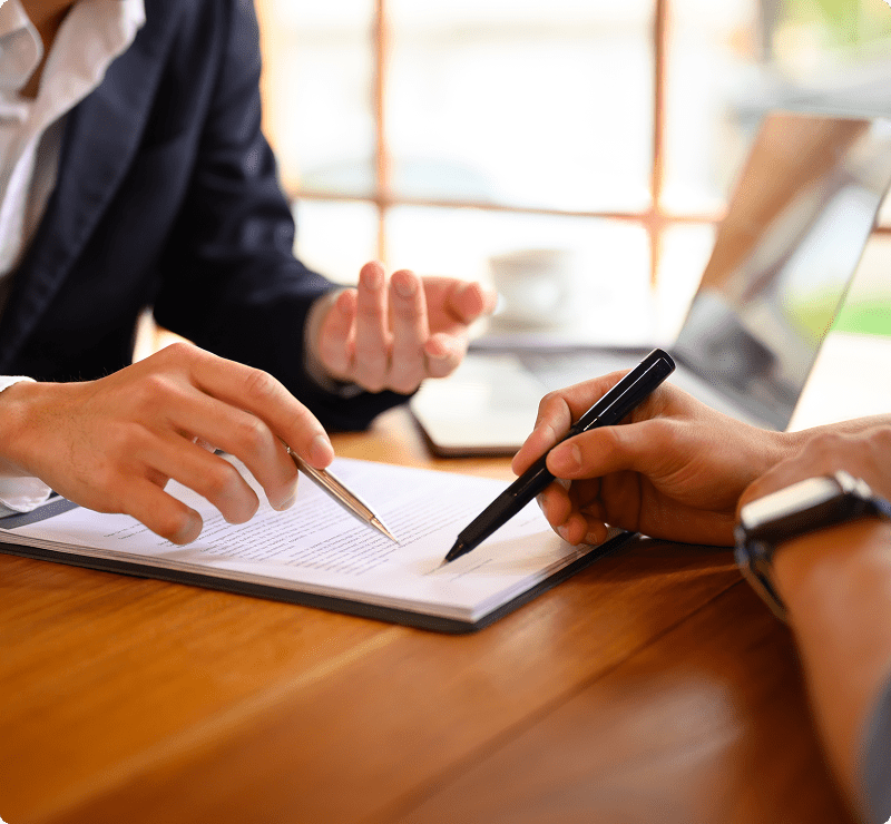 Two people are sitting at a table and one is holding a pen